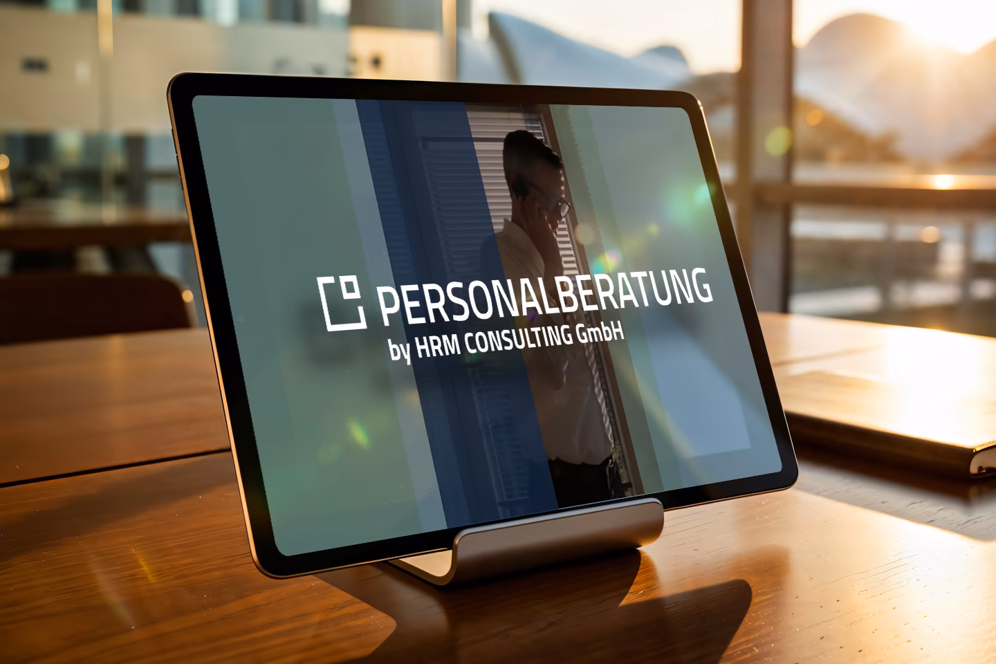 Tablet mit Logo Personalberatung by HRM Consulting GmbH auf einem Holztisch im Abendlicht
