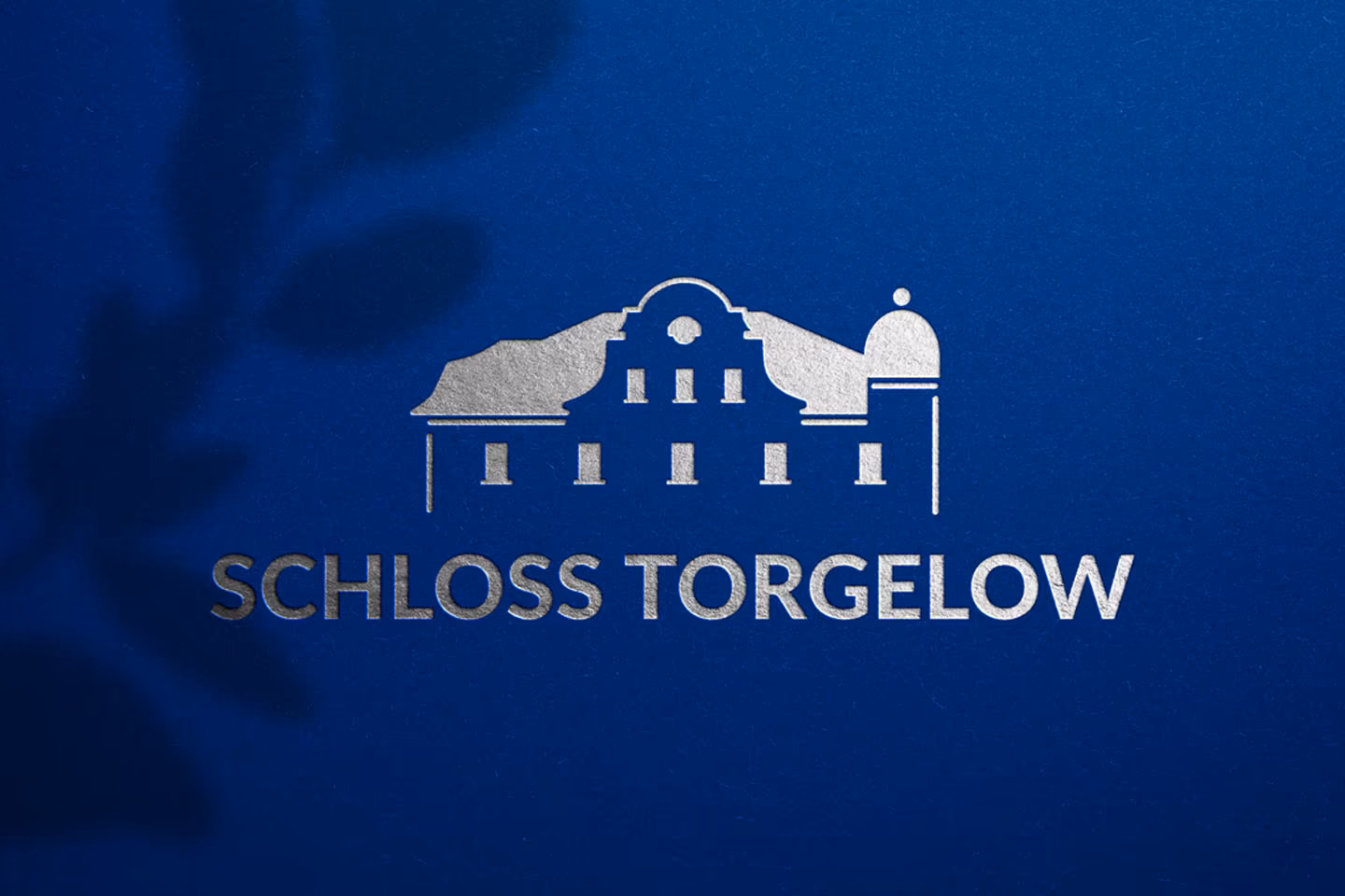 Logo Schloss Torgelow mit Silberfolienpr&auml;gung auf dunkelblauem Hintergrund